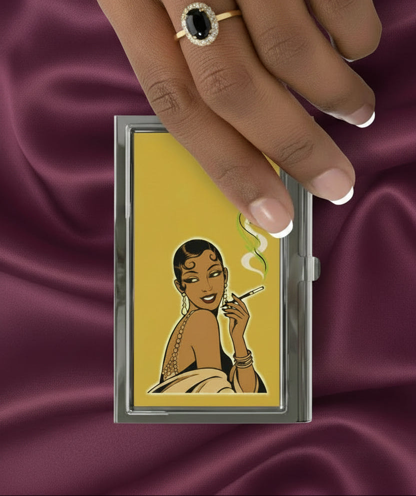 A rectangular metal cigarette case with a glossy finish, featuring a retro-style illustration of a woman smoking on a mustard yellow background.